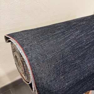 May include: A roll of dark blue denim fabric with a red, white, and blue selvedge edge.