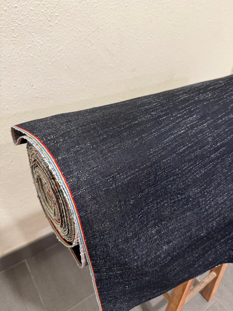 May include: A roll of dark blue denim fabric with a red, white, and blue selvedge edge.