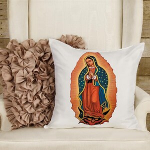 May include: White pillow with a colorful image of the Virgin Mary of Guadalupe. The image is surrounded by a golden halo with blue stars.