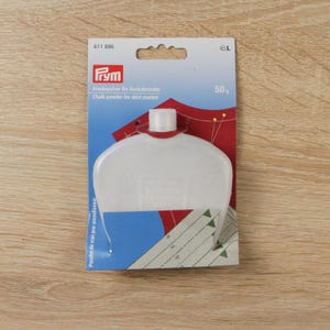 Puede incluir: Un dispensador de polvo de tiza de plástico blanco para marcadores de falda, con el texto "Fym" y "Chalk powder for skirt marker". El paquete incluye 50g de polvo de tiza y está sobre una superficie de madera.