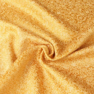 Peut inclure: Gros plan sur un tissu jaune doré avec un motif floral délicat. Le tissu est drapé, montrant des plis souples et un éclat subtil. Le motif floral blanc est uniformément réparti sur la surface.
