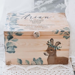 Puede incluir: Una caja de madera para recuerdos con un acabado marrón claro y un diseño floral. La caja tiene una tapa con bisagras, una pequeña perilla y una ilustración de un ciervo. El texto en la caja dice "Arian 14.10.2023 04:23 Uhr 4340g 55 cm Denn er hat seinen Engeln befohlen, dass sie dich behüten auf allen deinen Wegen. (Psalm 91,11)"