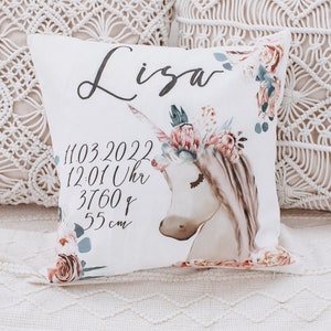 May include: White pillow with a unicorn and floral design. The pillow has the name "Lisa" and the text "11.03.2022 12:01 Uhr 3760g 55 cm" printed on it.