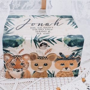 Op de afbeelding: Houten herinneringsdoos met een jungle-thema. Het heeft een tijger, leeuw en luipaardjong die hoofdbanden dragen. De doos is gepersonaliseerd met de naam "Jonah" en de datum "22.12.2021", tijd "19:30 Uhr", gewicht "3480 g" en hoogte "51 cm".