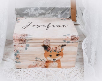 May include: Wooden keepsake box featuring a hand-painted fox wearing a floral crown. The box is decorated with floral accents and the name "Josefine" in script. The box is light brown with a natural wood grain.