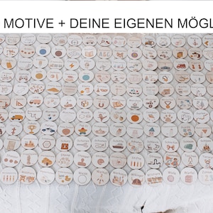 May include: A collection of 200 wooden circles with various illustrations and German words. The circles are arranged in rows on a white surface. The text "200 MOTIVE + DEINE EIGENEN M&Ouml;GLICH" is at the top of the image.