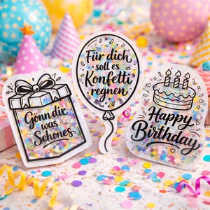 May include: Three clear, confetti-filled gift tags with black outlines. One says "Gönn dir was Schönes", another says "Für dich soll es Konfetti regnen", and the last says "Happy Birthday". Colorful confetti and party decorations are scattered around.