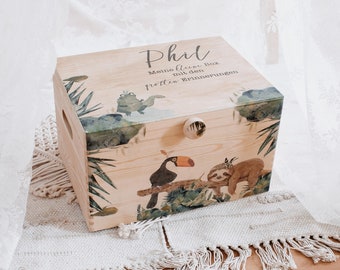 May include: A wooden box with a jungle theme. The box is decorated with a toucan, a sloth, and tropical leaves. The text "Phil, Meine kleine Box mit den tollen Erinnerungen" is printed on the lid.