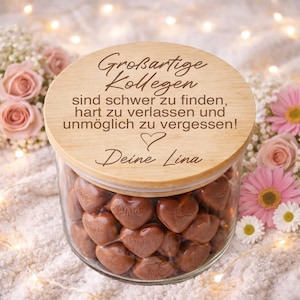 Könnte beinhalten: Eine weiße Keramik-Tasse mit schwarzem Henkel und dem Text "But First, Coffee" in schwarzer, handschriftlicher Schrift. Die Tasse steht auf einer weißen Oberfläche.