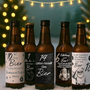 以下が含まれることがあります： 黒いキャップと白いラベルが付いた、茶色のビール瓶が5本。ラベルには数字とドイツ語のテキストがあり、「One Bier」や「Nikolaus ohne Bier?」などがあります。ボトルは雪景色の中に配置され、背景にはクリスマスライトがあります。