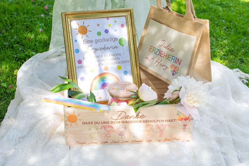 May include: A wooden box, framed print, and tote bag with a gift theme. The box has a sun graphic and text. The framed print has a rainbow and text. The tote bag has text and a heart graphic. Flowers and a jar are also present.