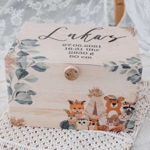Può includere: Una scatola di legno per ricordi con una finitura in legno chiaro e un design floreale. La scatola è decorata con un motivo a foglie di eucalipto in stile acquerello e una scena di animali del bosco fantasiosa. Il coperchio è inciso con il nome "Lukas", la data "27.05.2021", l'ora "16:31 Uhr", il peso "2930 g" e la lunghezza "50 cm".