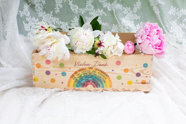 May include: Wooden crate decorated with colorful polka dots and a rainbow design, filled with white and pink peonies. The crate has text in German, including "Vielen Dank."