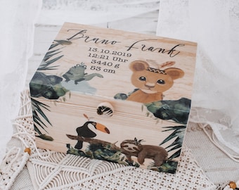 May include: Wooden keepsake box with a jungle theme. The box is decorated with a lion, toucan, sloth, and frog. The box has a label that reads "Bruno Frank 13.10.2019 12:21 Uhr 3440 g 53 cm".