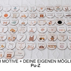 May include: A set of 200 round wooden tokens with various illustrations and German words. The tokens are arranged in rows on a white fuzzy surface. The text at the bottom of the image reads "200 MOTIVE + DEINE EIGENEN M&Ouml;GLICH Pu-Z".