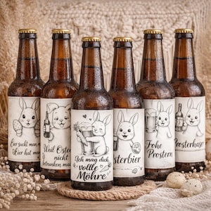 Puede incluir: Seis botellas de cerveza marrones con tapas doradas y etiquetas blancas con conejos de dibujos animados. Las etiquetas tienen texto e ilustraciones en alemán. Las botellas están dispuestas sobre una superficie de madera.