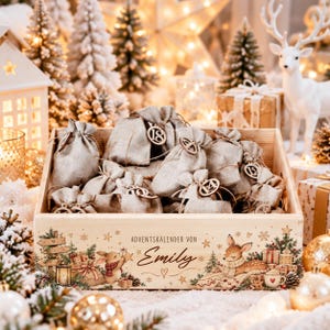 May include: A wooden crate filled with small gray fabric drawstring bags, each featuring a circular wooden tag with a number. The front of the crate is decorated with illustrations of a rabbit and a deer, and the text "ADVENTSKALENDER VON Emily".