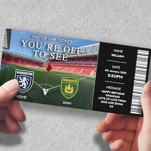 Op de afbeelding: Een gepersonaliseerd wedstrijdticket met de tekst "YOU'RE OFF TO SEE" boven een stadionafbeelding. Het ticket bevat teamlogo's, datum, tijd, naam en een verjaardagsbericht.