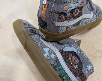 May include: A pair of gray high-top sneakers with a brown sole. The sneakers feature colorful illustrations of characters from a popular animated movie. The design includes a rooster, a woman with a spear, and other tropical elements.