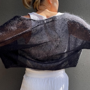 May include: A black sheer knitted cardigan with a loose fit. The cardigan is made of a lightweight, breathable fabric and has a relaxed, casual style.
