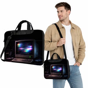 May include: Black laptop bag featuring a retro computer monitor with a colorful, static-like display. The bag has a handle and a shoulder strap. A smaller matching bag is also visible.