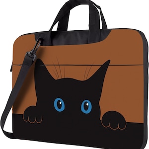 May include: A laptop bag featuring a black cat design with blue eyes peeking out. The bag has a brown background and a black handle and shoulder strap. The bag is designed to carry a laptop.