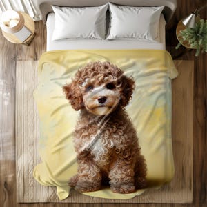 May include: A soft, yellow fleece blanket with a brown and white dog sitting on it. The dog has curly fur and is looking at the camera.