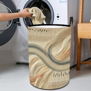 May include: A beige and brown laundry hamper with a black top and a geometric pattern of lines and swirls. The hamper is standing next to a white washing machine.