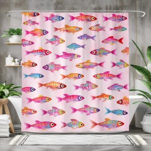 May include: A pink shower curtain featuring a repeating pattern of colorful watercolor fish. The fish are in shades of pink, orange, yellow, blue, and purple, with black and white eyes. The curtain hangs in front of a white bathtub.