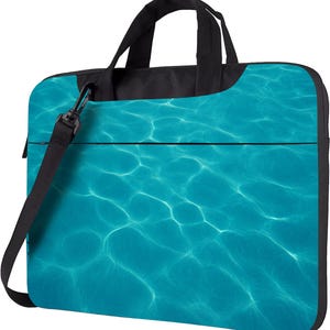 Könnte beinhalten: Laptoptasche mit einem türkisfarbenen Wassermuster. Sie hat einen schwarzen oberen Teil, Griffe und einen abnehmbaren Schultergurt. Das Design erweckt den Eindruck von Sonnenlicht, das sich auf der Wasseroberfläche spiegelt.