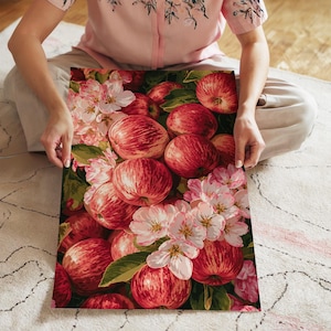 May include: A rectangular print featuring a vibrant botanical illustration of numerous red and yellow striped apples interspersed with clusters of delicate pale pink and white apple blossoms and green leaves, creating a dense, colorful composition.