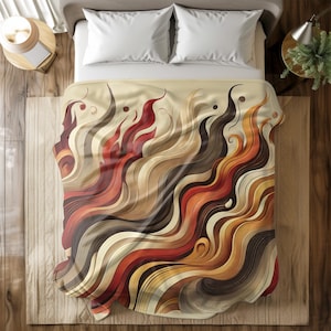 May include: A beige blanket with a flowing, abstract design in shades of red, brown, orange, and cream. The pattern resembles stylized waves or flames, creating a warm and inviting aesthetic. The blanket is on a bed with white pillows.