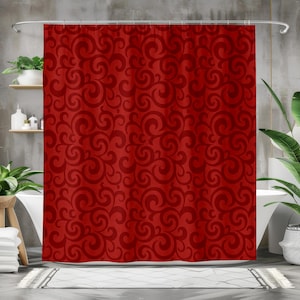 May include: A red shower curtain featuring a repeating pattern of swirling, scroll-like designs. The curtain hangs in front of a white bathtub. The bathroom has a neutral colour scheme with plants and shelves.