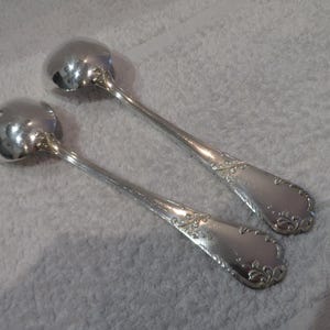 Peut inclure: Deux cuillères à salade en argent avec des manches ornés. Les cuillères présentent un motif décoratif floral.