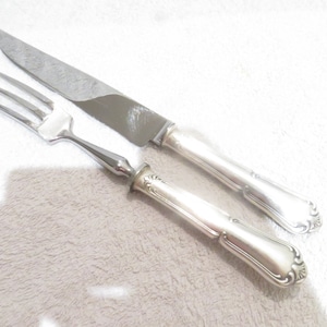 May include: A silver fork and knife set with ornate handles. The fork has three prongs and the knife has a serrated blade.