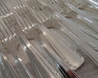 May include: A close-up of a set of silver forks, arranged in a fan shape. The forks are shiny and reflect light.