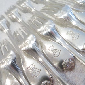 Puede incluir: Un juego de tenedores de plata con mangos ornamentados. Cada tenedor tiene una inicial con monograma en el mango.