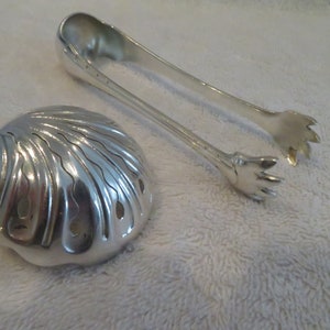 May include: Silver serving set with a shell-shaped serving spoon and a pair of tongs with claw-like ends.