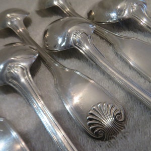 Puede incluir: Juego de seis cucharas de plata con mangos ornamentados. Las cucharas tienen un cuenco redondeado y un diseño decorativo en el mango.
