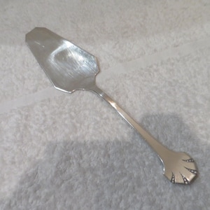 Può includere: Un servizio per torta in argento con un manico decorativo. Il manico ha un design a festoni.