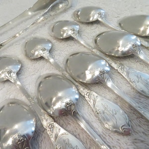 Puede incluir: Un juego de diez cucharas de plata con mangos ornamentados. Las cucharas tienen un diseño floral y están en excelente estado.