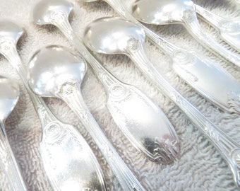 May include: A set of silver spoons with ornate handles. The spoons are arranged in a row, with the handles facing the viewer. The spoons are polished and shiny.