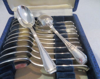 May include: A collection of silver spoons presented in a blue velvet-lined box. The spoons, with their reflective surfaces and ornate handles, are neatly arranged. The open box displays a full set of silverware.