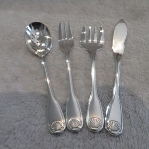 May include: Set of four silver-plated utensils with a seashell design on the handles. The set includes a spoon, two forks, and a butter knife.