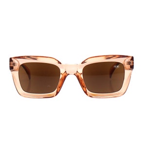 May include: A pair of peach-colored square-shaped sunglasses with brown lenses. The sunglasses have a +2.50 magnification.