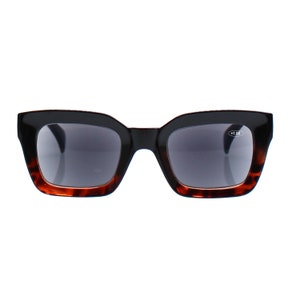 Puede incluir: Gafas de lectura negras y de carey con una graduación de +1,00. Las gafas tienen una montura cuadrada con bordes redondeados.