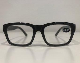 Könnte beinhalten: Schwarze rechteckige Lesebrille mit klaren Gläsern. Die Brille hat eine +3,00 Vergrößerung.