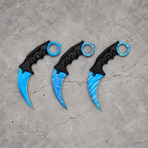 Könnte beinhalten: Drei Karambit-Messer mit schwarzen, strukturierten Griffen und Fingerringen. Die erste Klinge ist einfarbig hellblau, die zweite zeigt ein weißes Spinnennetzmuster auf blauem Grund und die dritte hat ein weißes Streifenmuster auf Blau.
