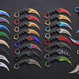 May include: A collection of curved karambit knives arranged in rows, featuring various blade finishes including rainbow, solid colours, spiderweb patterns, skull prints, and marble designs, all with black ergonomic handles and finger ring pommels.