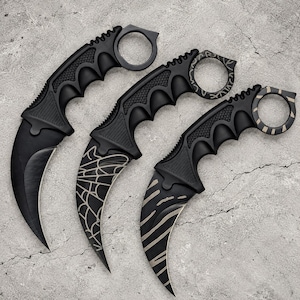 Peut inclure: Trois couteaux karambit noirs avec des lames courbes et des anneaux de doigt. Le premier couteau est noir uni, le deuxième présente un motif de toile d'araignée blanche sur la lame et l'anneau, et le troisième a un motif rayé blanc.